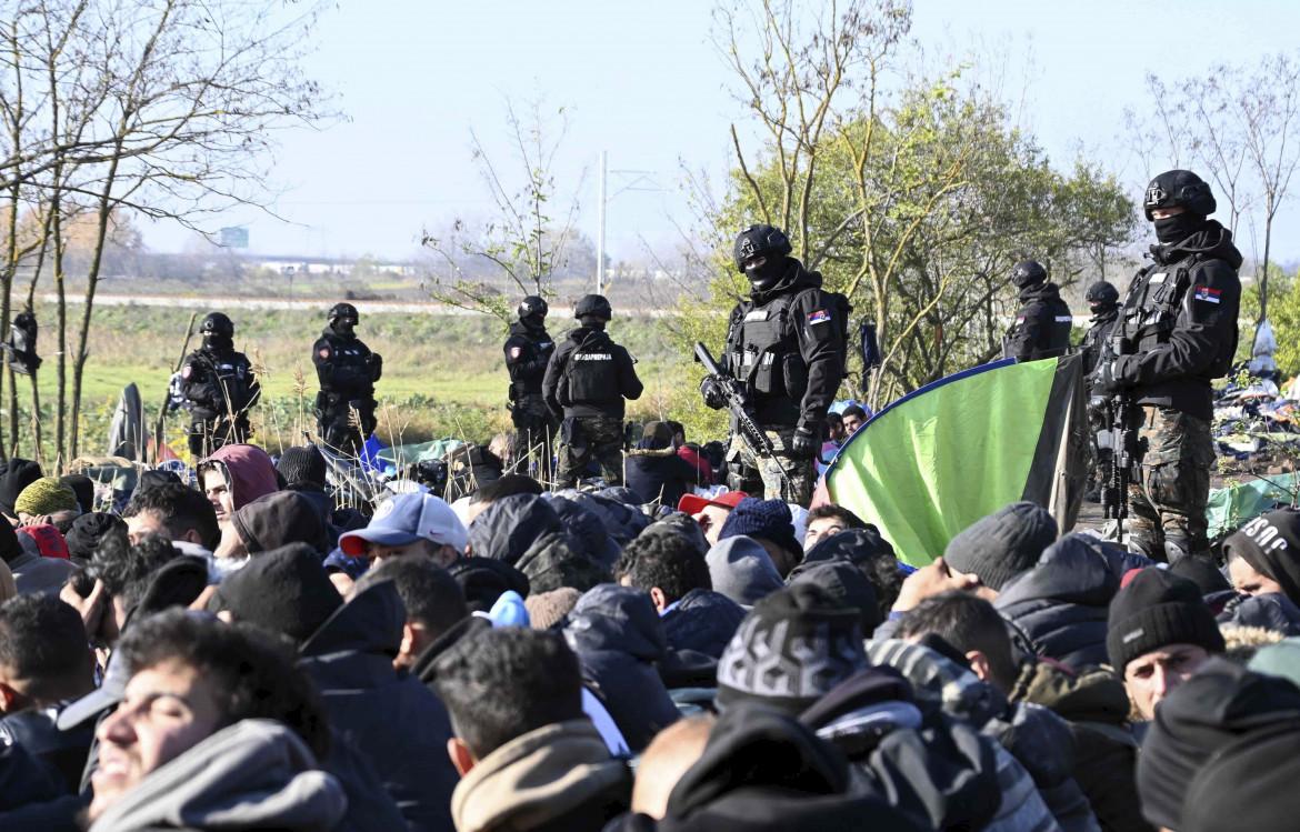 Agenti di polizia controllano un gruppo di migranti nei pressi della città di Horgos, Serbia. foto Ap