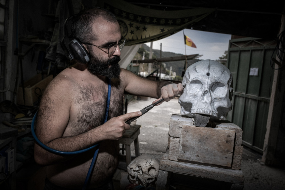 07-scultore-carrarino-durante-la-lavorazione-di-un-piccolo-blocco-di-marmo-modellato-a-forma-di-teschio-all-interno-dell-atelier-bedrock-cava-scuola