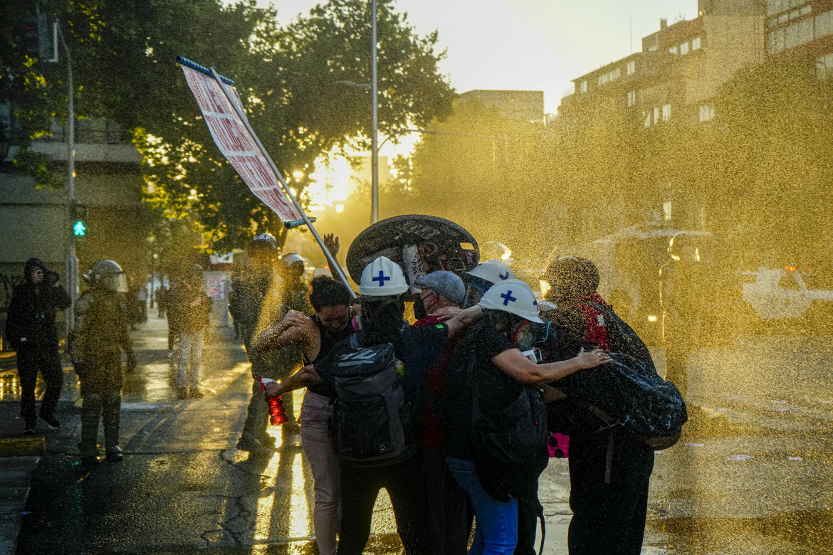 Dimostranti colpiti dai gas lacrimogeni si accalcano durante una commemorazione per l’anniversario delle rivolte del 2019-20 a Santiago, in Cile (Esteban Felix, Ap)