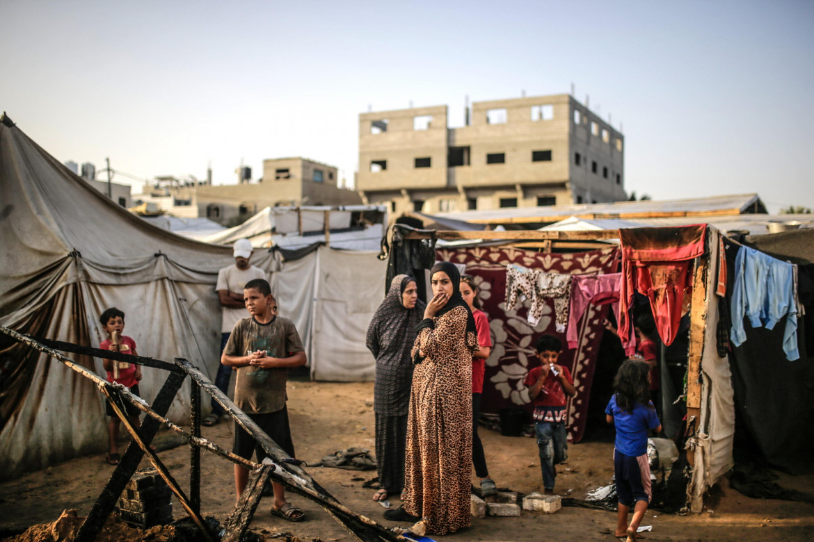 Alcuni palestinesi esaminano i resti in un campo per sfollati interni nei locali dell’ospedale al-Aqsa, dopo che la zona è stata colpita da un attacco aereo israeliano, a Deir al Balah (Mohammed Saber, Ansa)