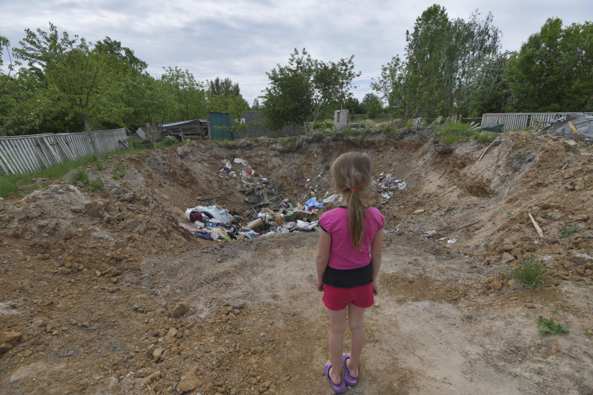 Una bambina di fronte al cratere provocato da una bomba a Malyn foto Ap