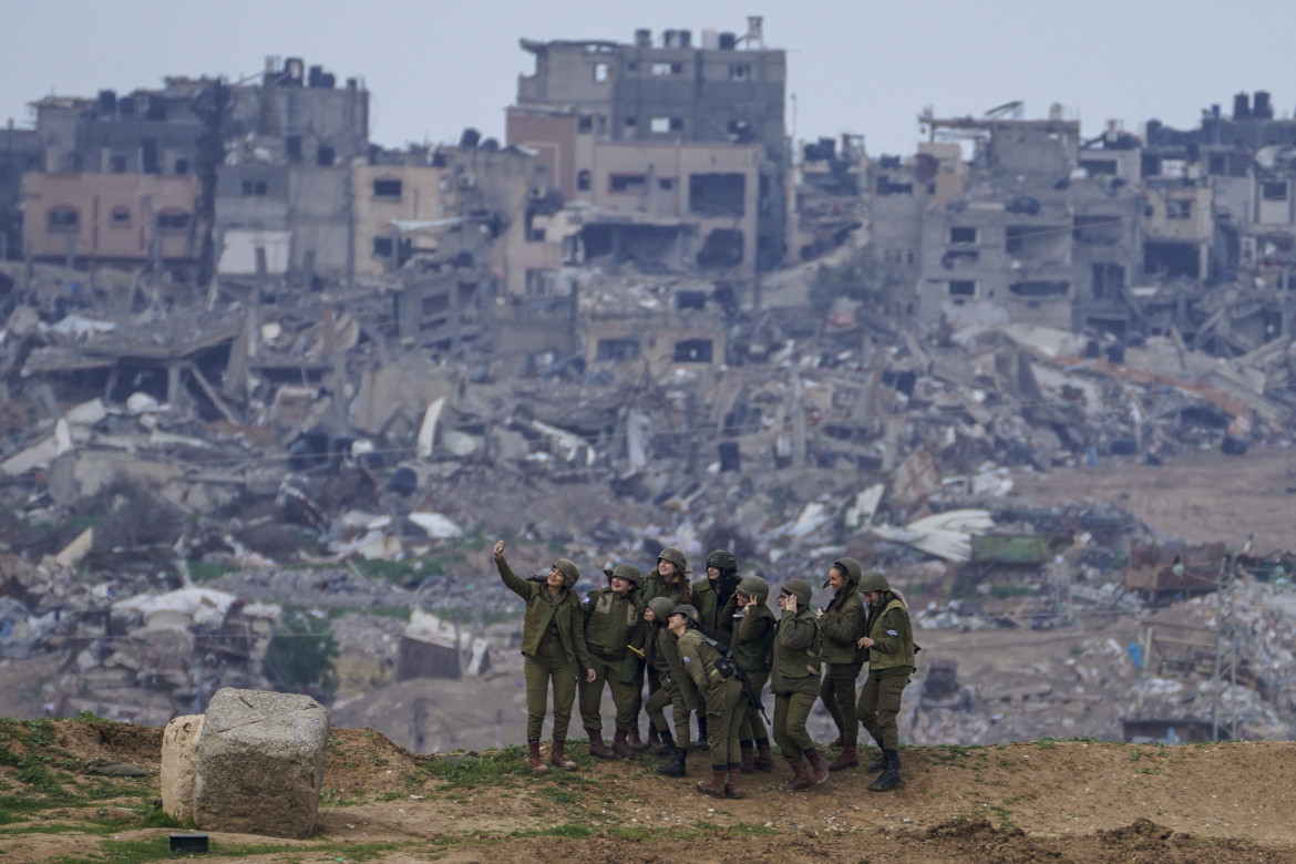 Soldati dell’Idf posano davanti a delle macerie a Gaza foto Ap