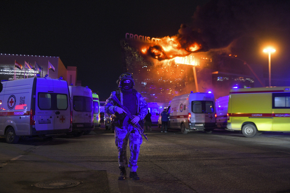 Un militare russo protegge un'area mentre un enorme incendio divampa al Crocus City Hall, a Mosca, a seguito di un attacco armato foto Ap