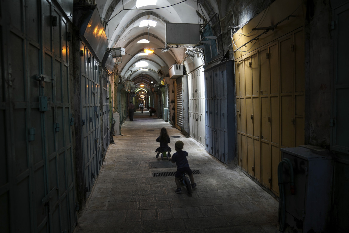 Bambini palestinesi giocano tra i negozi chiusi della città vecchia di Gerusalemme foto Ap/Mahmoud Illean