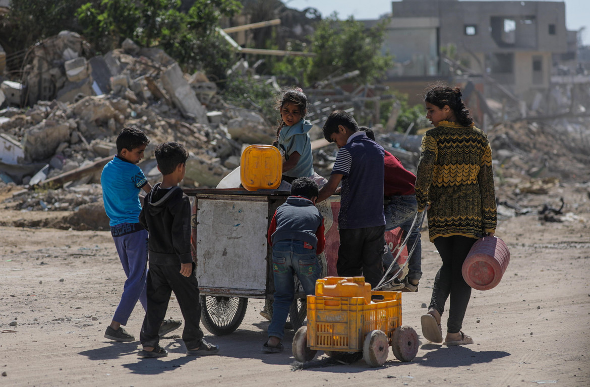 Un gruppo di ragazzini palestinesi in cerca di acqua nella città di Khan Younis, nel sud della Striscia di Gaza