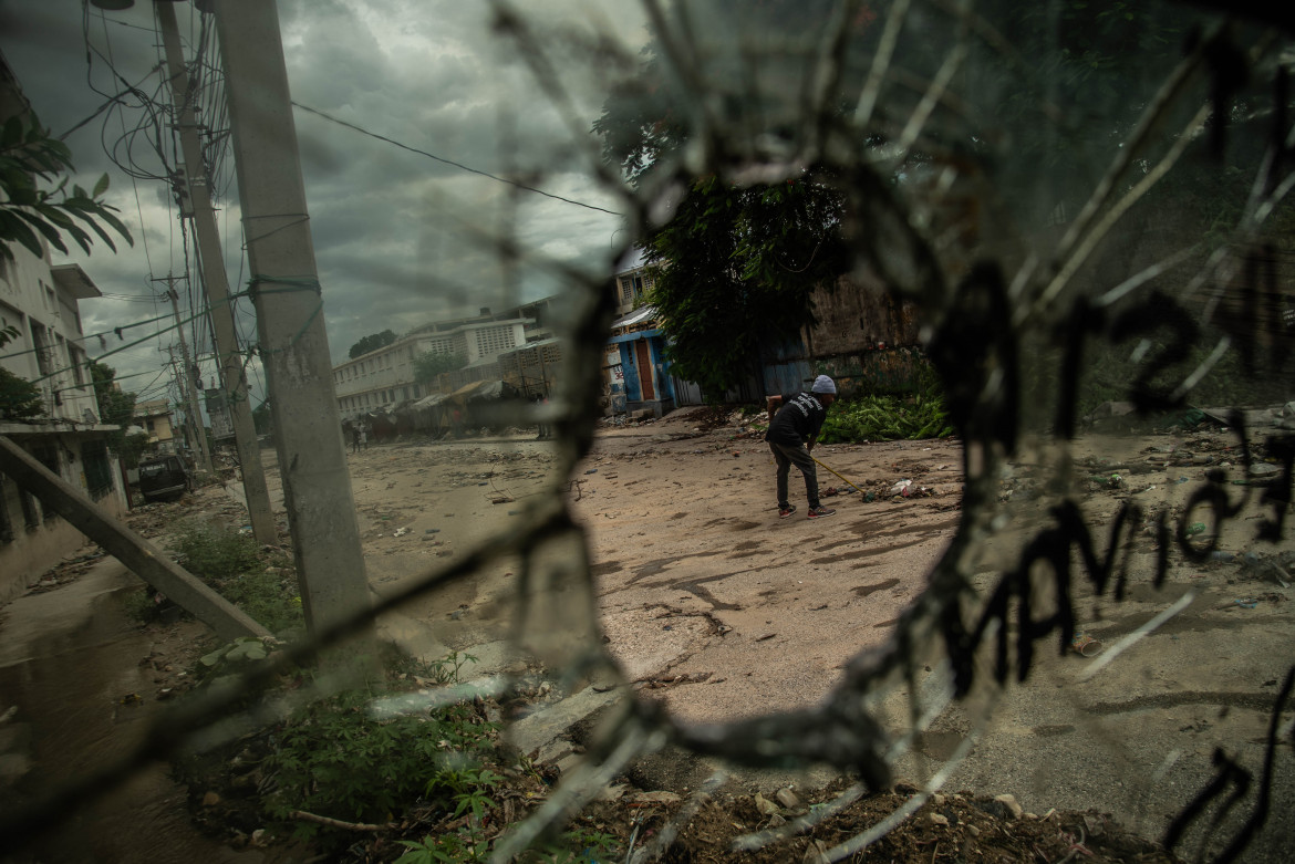 Un abitante di Port-Au-Prince pulisce la strada dai detriti degli scontri tra bande di Haiti foto di Hector Adolfo Quintanar Perez/Ansa