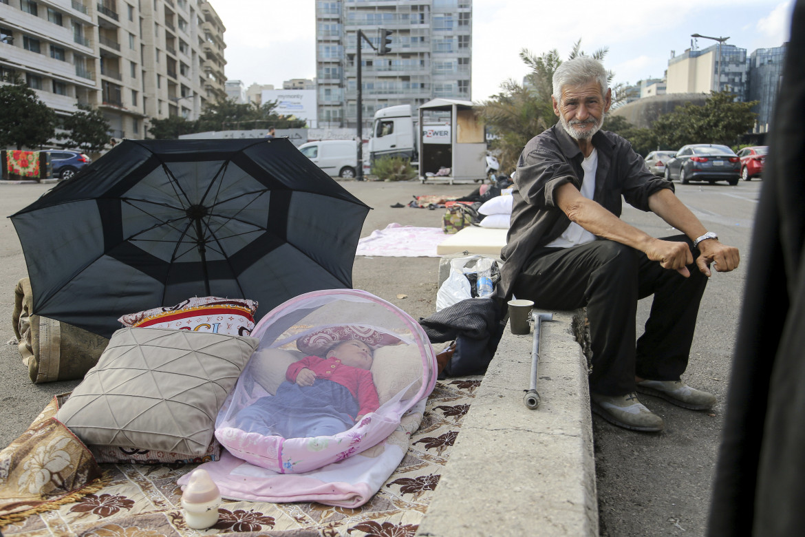 Un anziano libanese sfollato insieme alla nipotina per le strade di Beirut foto Ap/Marwan Naaman