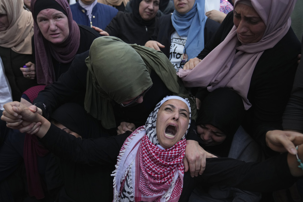 Una donna palestinese piange mentre dà l'ultimo sguardo al corpo del figlio foto di Nasser Nasser/Ap