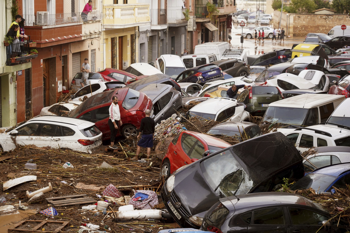 Residenti guardano le auto ammucchiate dopo essere state travolte dalle inondazioni a Valencia, in Spagna -foto LaPresse