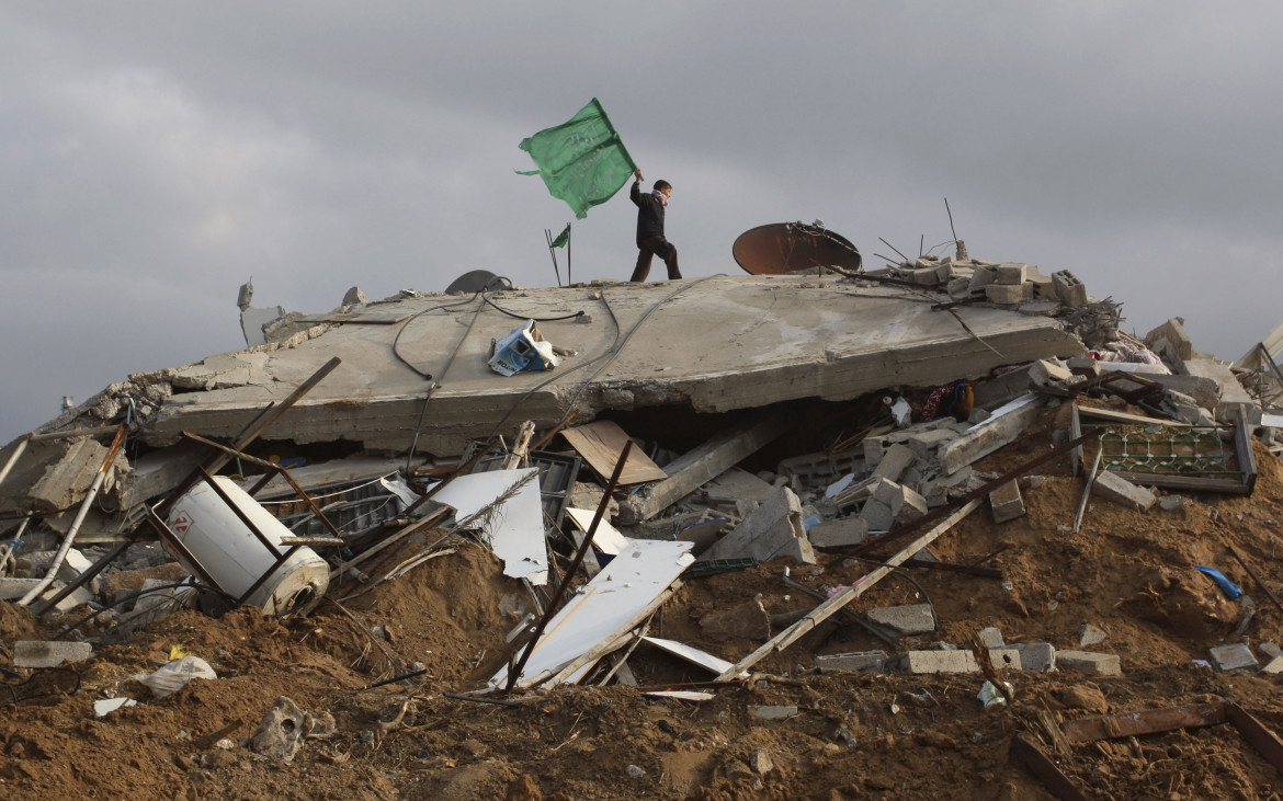 Un ragazzino tra le macerie di una casa a Beit Lahya con la bandiera verde di Hamas foto Ap/Hatem Moussa