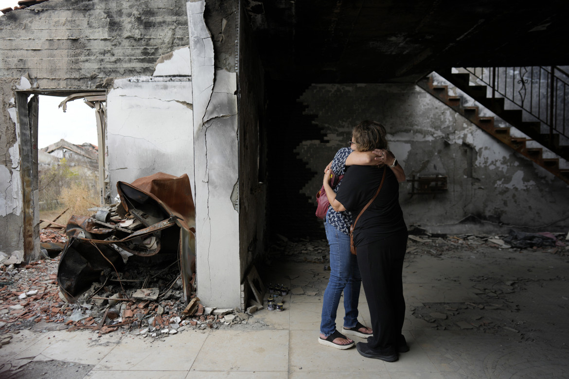 Persone si abbracciano tra le macerie del Kibbutz Be'eri durante il primo anniversario dall’attacco di Hamas