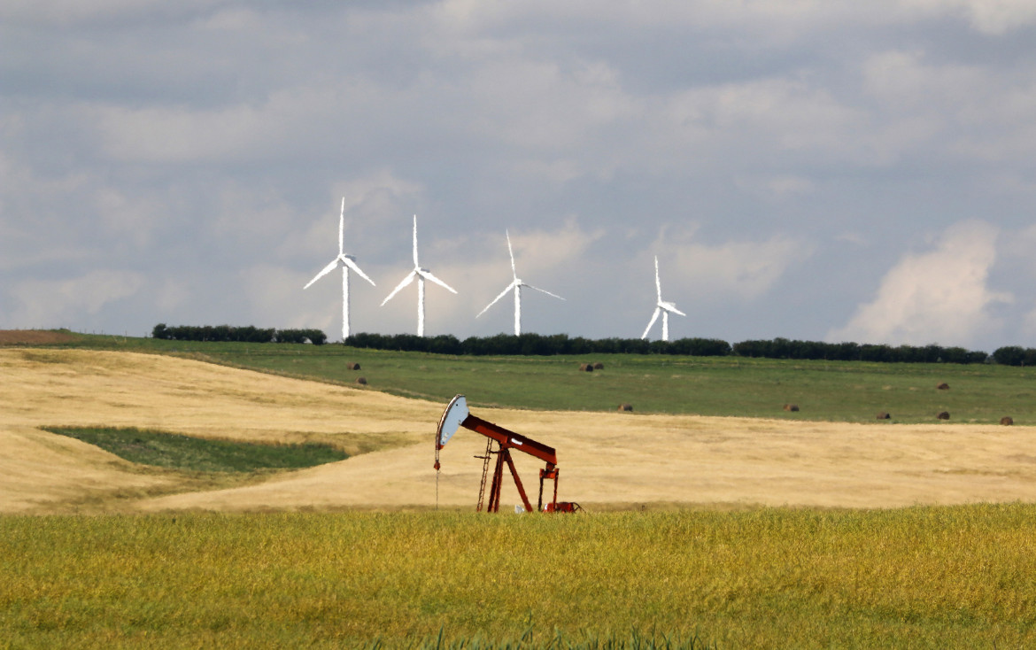 Una pompa per l'estrazione del petrolio in un campo con pale eoliche foto Ap