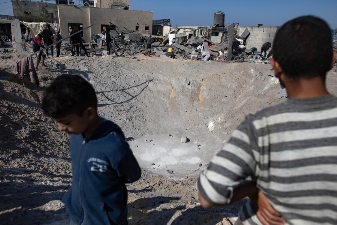 Palestinesi ispezionano un cratere dopo i bombardamenti israeliani in un campo che ospita sfollati interni a Khan Younis foto Haitham Imad/Ansa