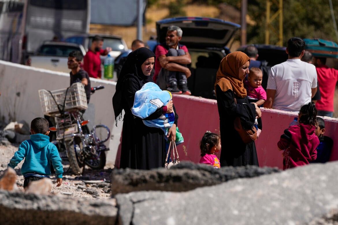 Sfollati attraversano il confine con la Siria, attraverso un cratere causato dagli attacchi aerei israeliani volti a bloccare l'autostrada Beirut-Damasco al valico di Masnaa in Libano foto Hassan Ammar/Ap