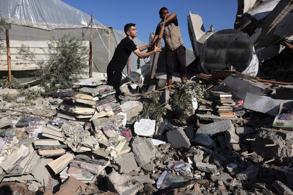 Alcuni palestinesi raccolgono libri dalle macerie di un centro culturale dopo un attacco israeliano a Rafah, nella Striscia di Gaza meridionale foto Mohammed Abed/Getty Images