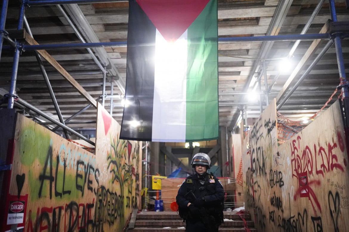 010-un-agente-di-polizia-in-piedi-sotto-una-bandiera-palestinese-dopo-un-raid-in-un-accampamento-nel-campus-dellucla-jae-c-hong-ap