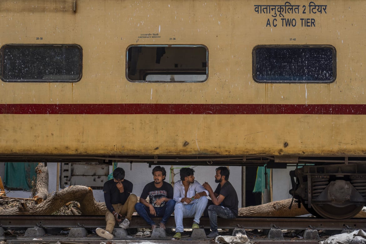 04-ragazzi-indiani-si-siedono-e-chiacchierano-allombra-sotto-un-vagone-ferroviario-fermo-a-mumbai-durante-londata-di-caldo-torrido-che-ha-investito-lindia-rafiq-maqbool-ap
