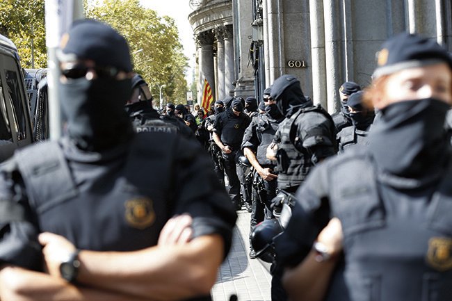 Spanish policemen keep watch in front of the regional Ministry of Economy's headquarters during a search, in Barcelona, northeastern Spain, on 20 September 2017. Spanish Civil Guard carried out different searches for documents related to the '1-O Referendum' resulting in the arrest of 14 people, including some Catalan Government's top officials, according to sources of the investigation. The police operation provocked a mass reaction with thousands of Catalan people taking the streets. EFE/Alejandro Garcia