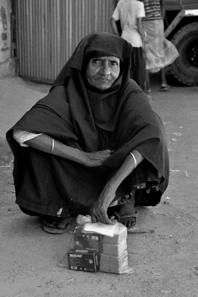 Una donna Rohingya aspetta all’esterno del punto per la distribuzione di cibo