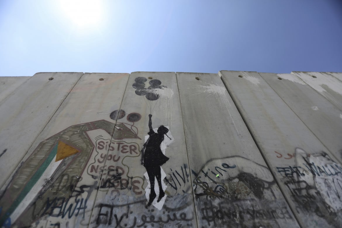 Un graffito di Banksy sul muro a Ramallah - foto Ap