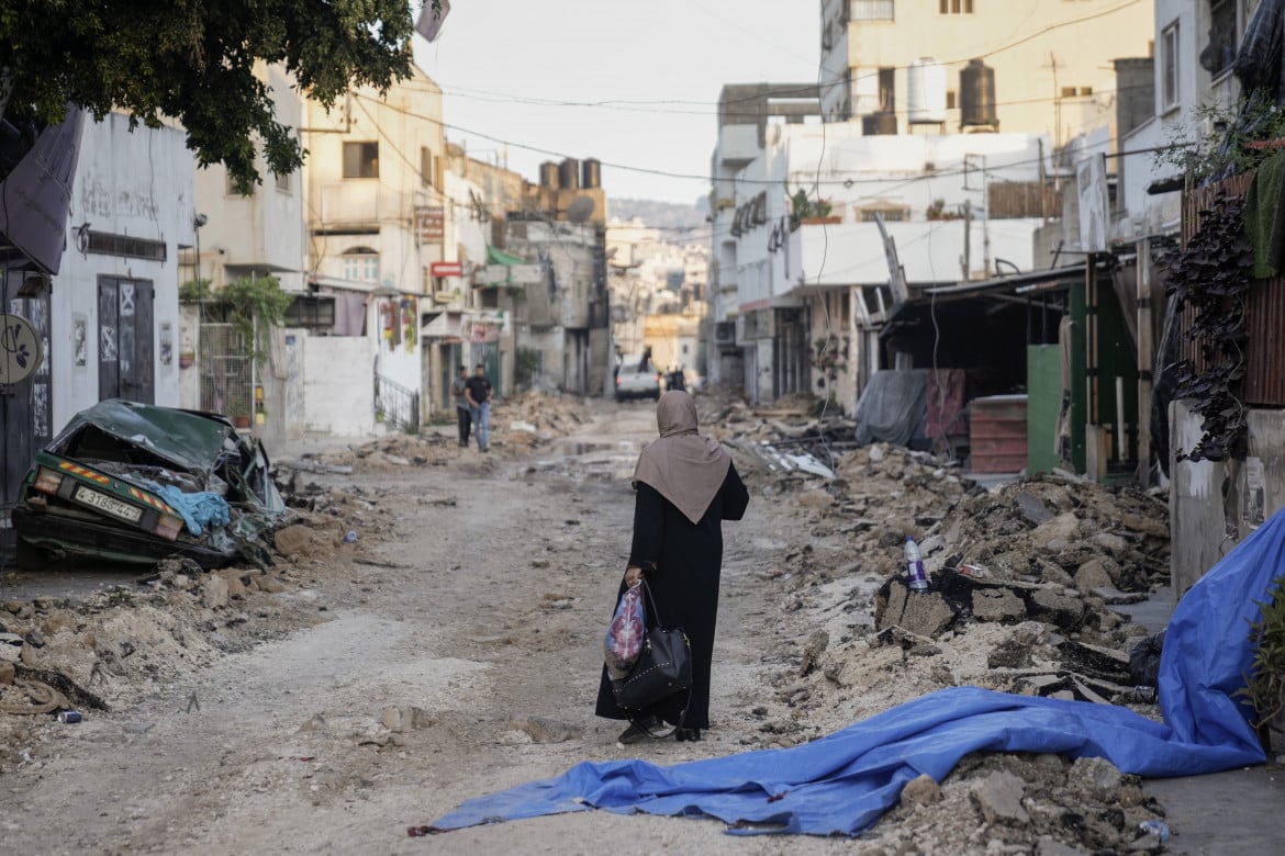Una donna palestinese cammina per le strade sventrate del campo profughi di Jenin foto Ap/Majdi Mohammed