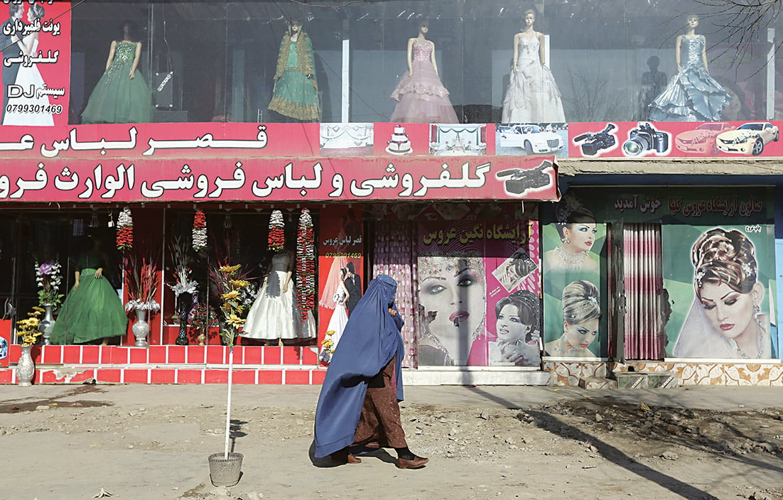 Kabul, una donna passa di fronte a un salone di bellezza chiuso foto Ap/Rahmat Gul