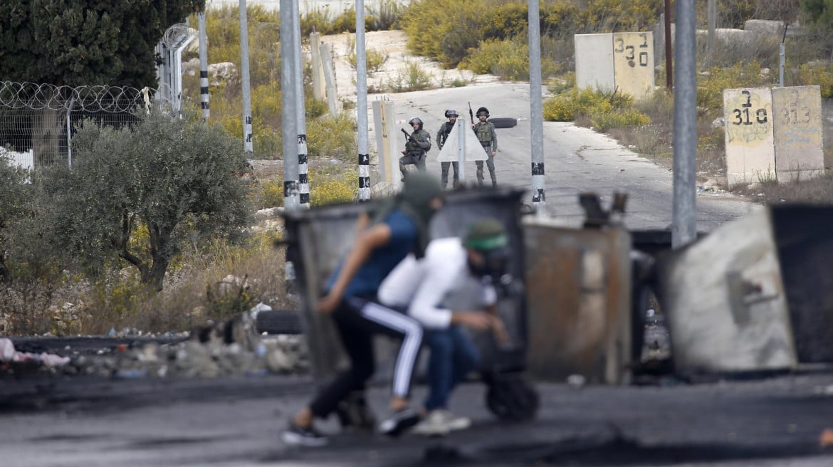 Palestinesi si riparano dalle truppe israeliane a Ramallah foto Ansa