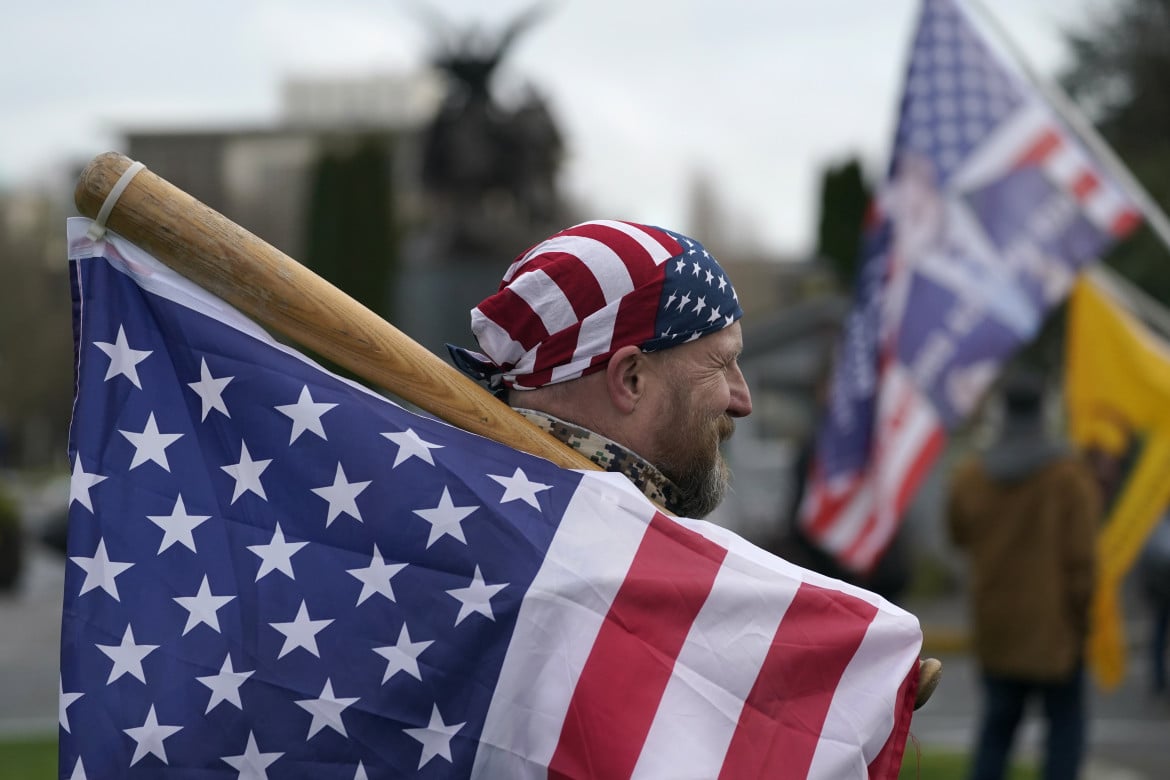 Un uomo con bandiera e mazza da baseball al Campidoglio di Washington, il 6 gennaio 2021