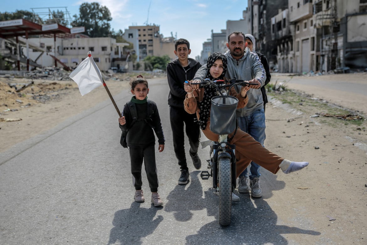 Una famiglia sfollata sventola una bandiera bianca mentre lascia Gaza City foto Afp