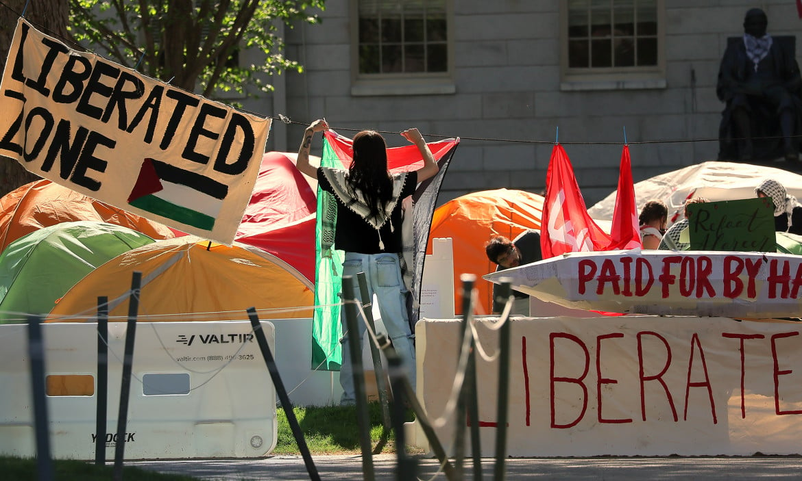 Un manifestante appende una bandiera palestinese nell'accampamento filo-palestinese di Harvard Yard a Cambridge