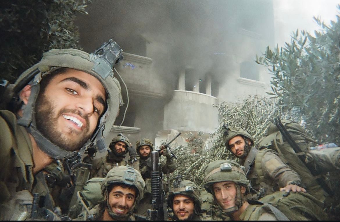 Soldati israeliani in posa per una foto davanti a case palestinesi in fiamme foto Twitter