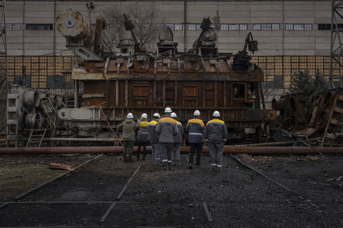Lavoratori delle centrali elettriche osservano il trasformatore di tensione distrutto dopo un attacco russo nell'Ucraina centrale foto Ap