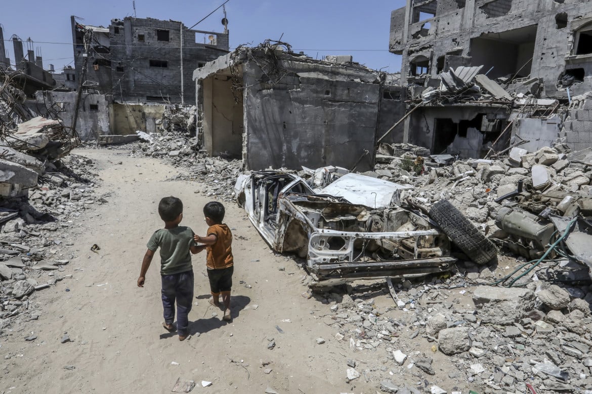 Dei bambini palestinesi camminano accanto a edifici distrutti a Deir al Balah foto Ap/Abed Rahim Khatib