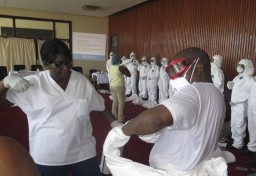 Un operatore dell'Oms mostra a un'infermiera di Freetown come indossare la tuta protettiva